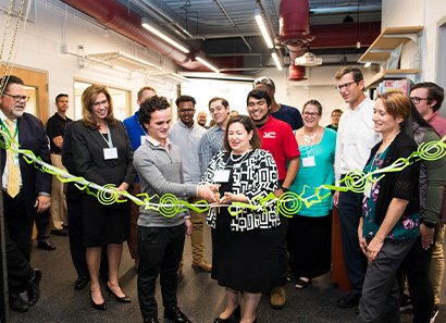 A group of people in an office cutting a ribbon
