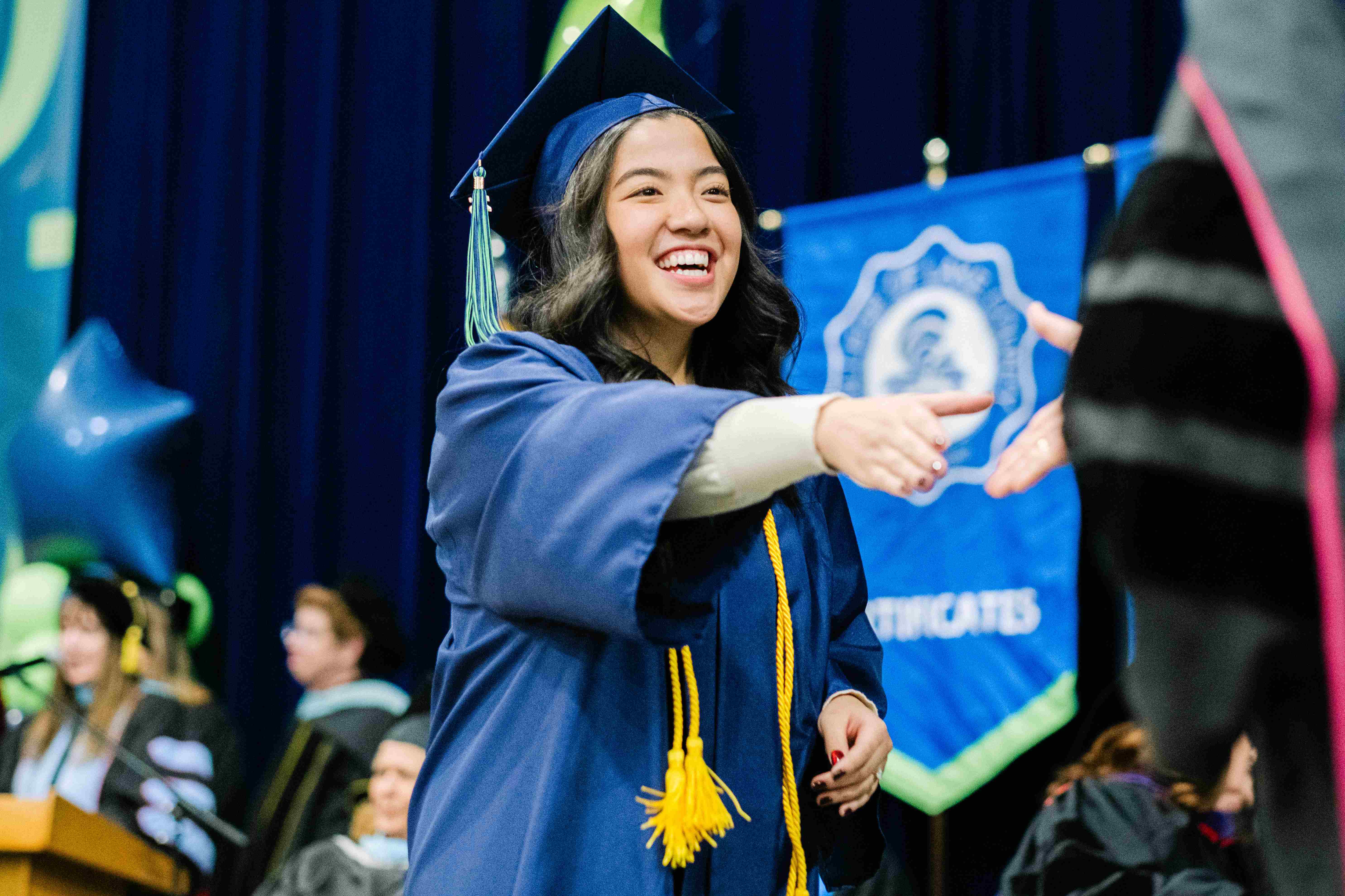A student shaking hands as they receive their diploma walking the stage