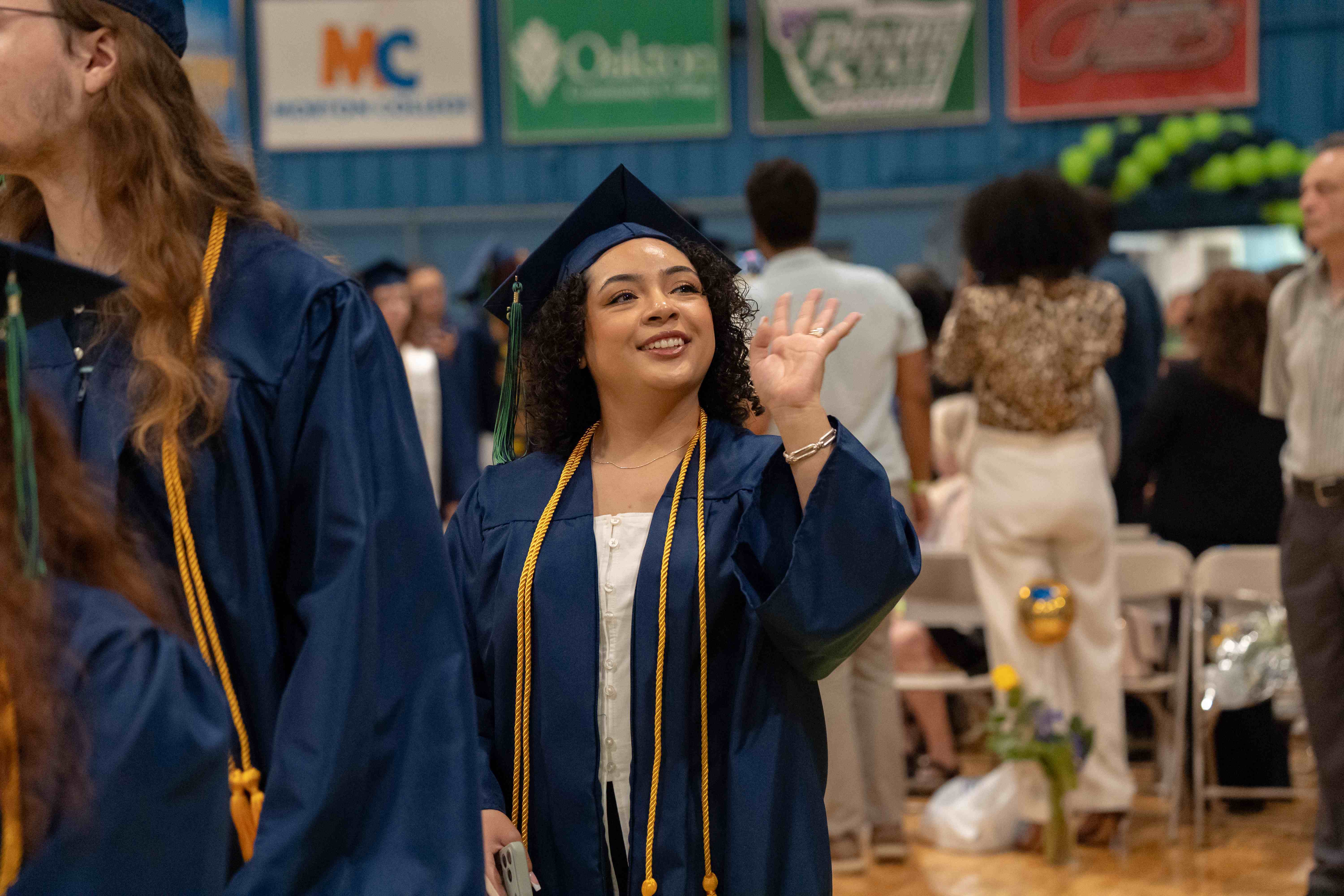 A graduate waving as they walk