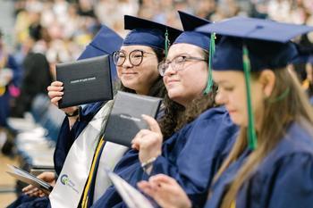A graduate smiling with her diploma
