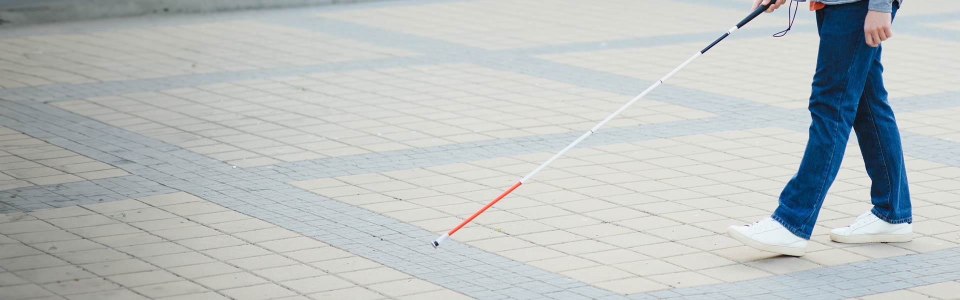 A visually impaired person walking with a mobility cane