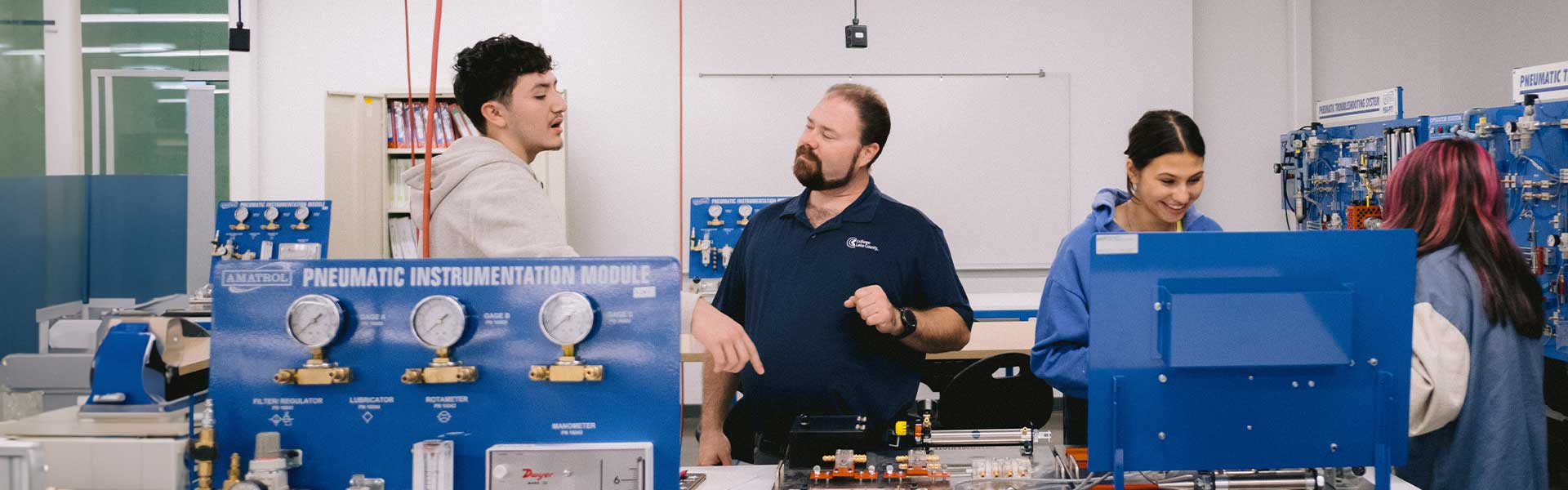 Four students and a teacher work on a project in a lab