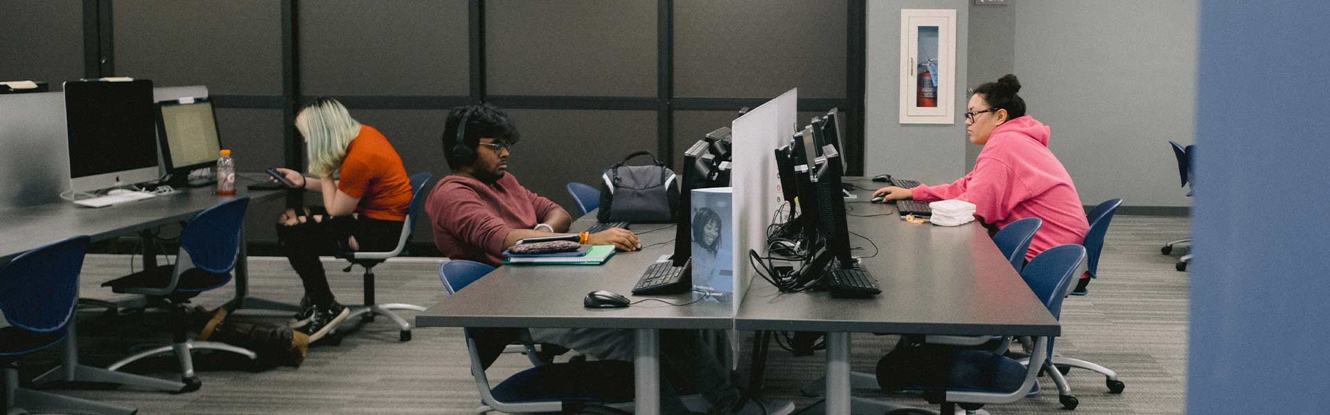 Three students in a dark computer lab