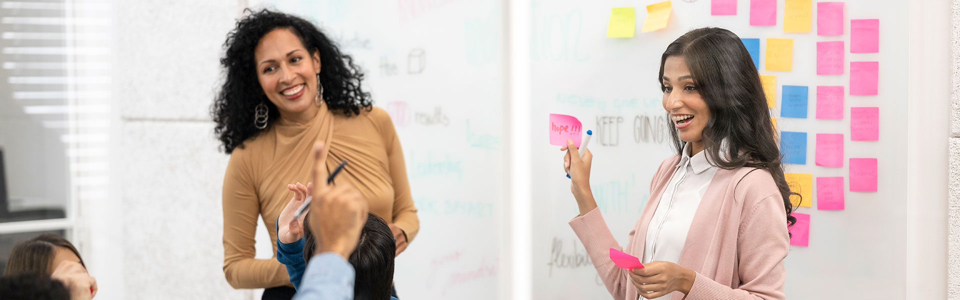 Two women leading a corporate training program using colorful sticky notes