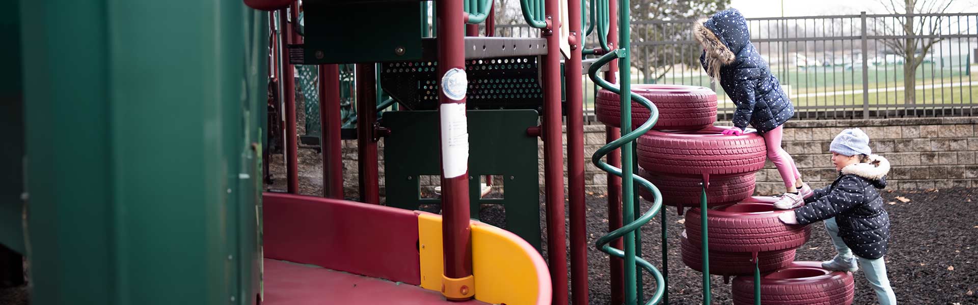 A group of small children playing on a pink and green playground