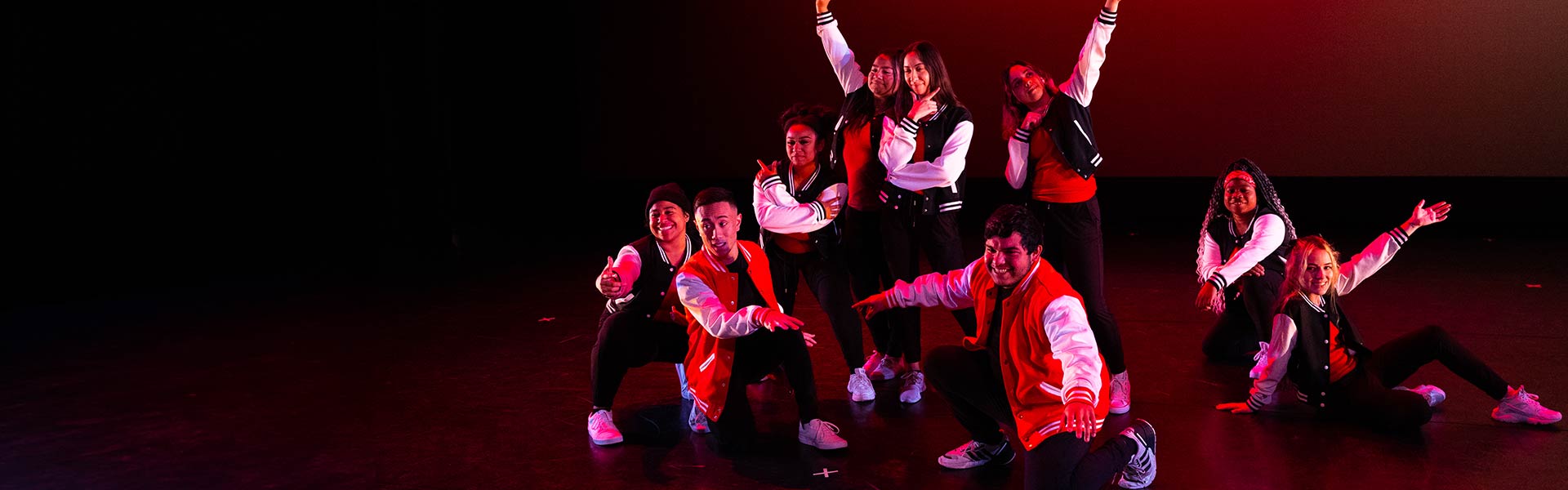 A group of dance students pose together on stage