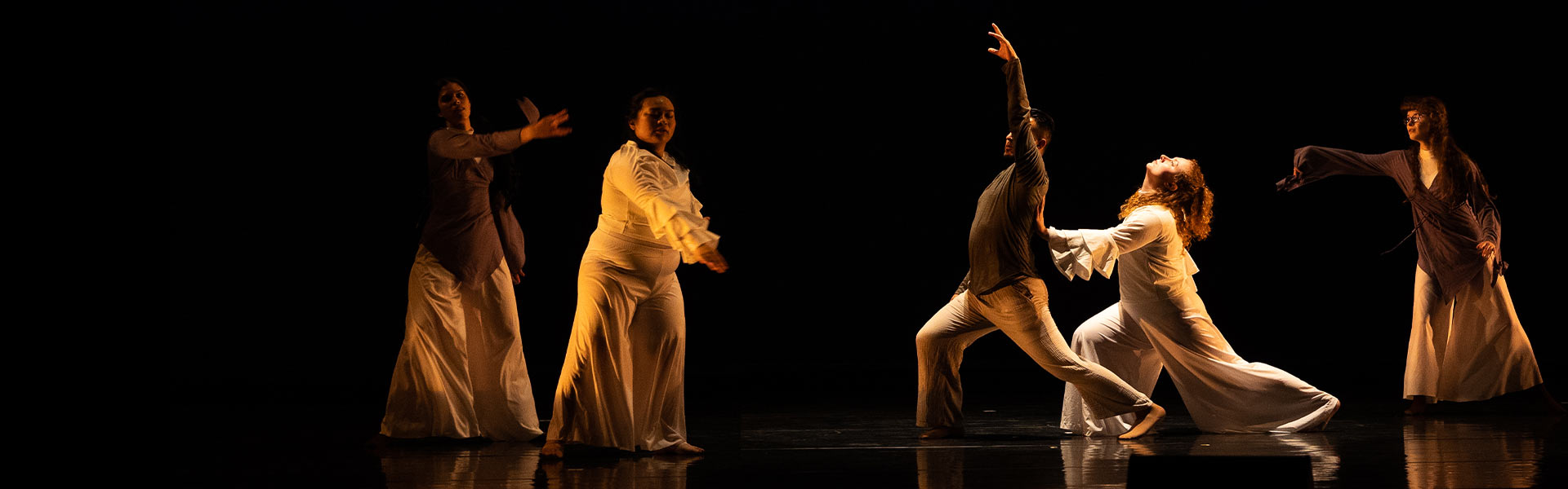 Five dancers pose on stage in white clothing