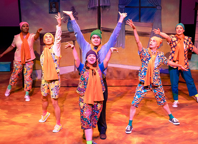 A group of students singing on stage with colorful costumes