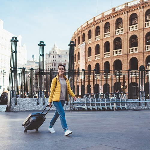 A student walking with her suitcase in Rome