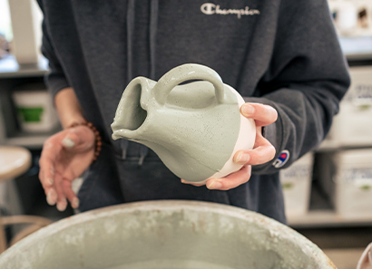 A person glazing a clay pot