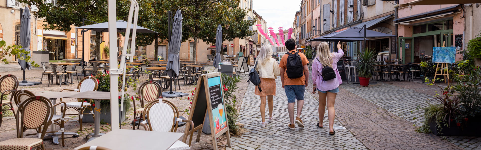 Students walking down sidewalk lined with cafes in France.