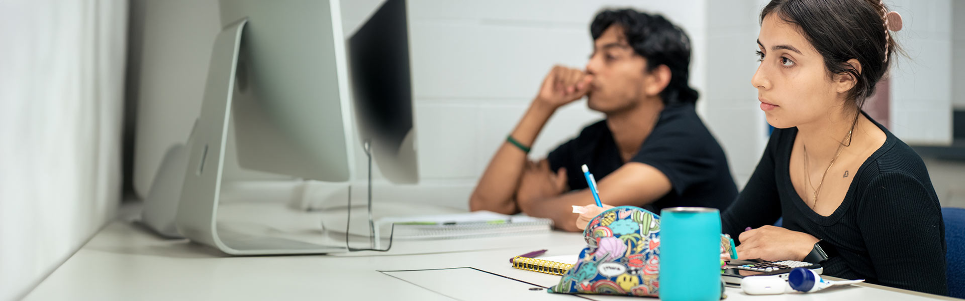 Two students taking notes in class.