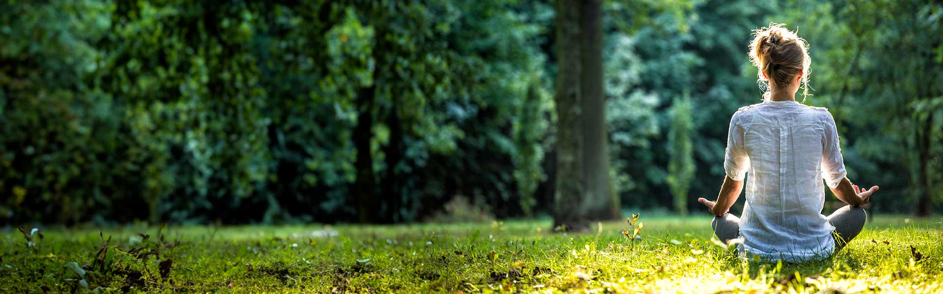 Woman meditates in a sunlit park