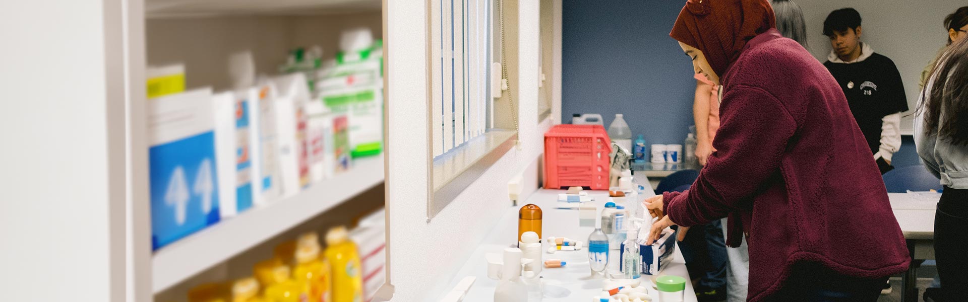 Female Pharmacy Technician student arranging different kinds of medicine bottles in class.