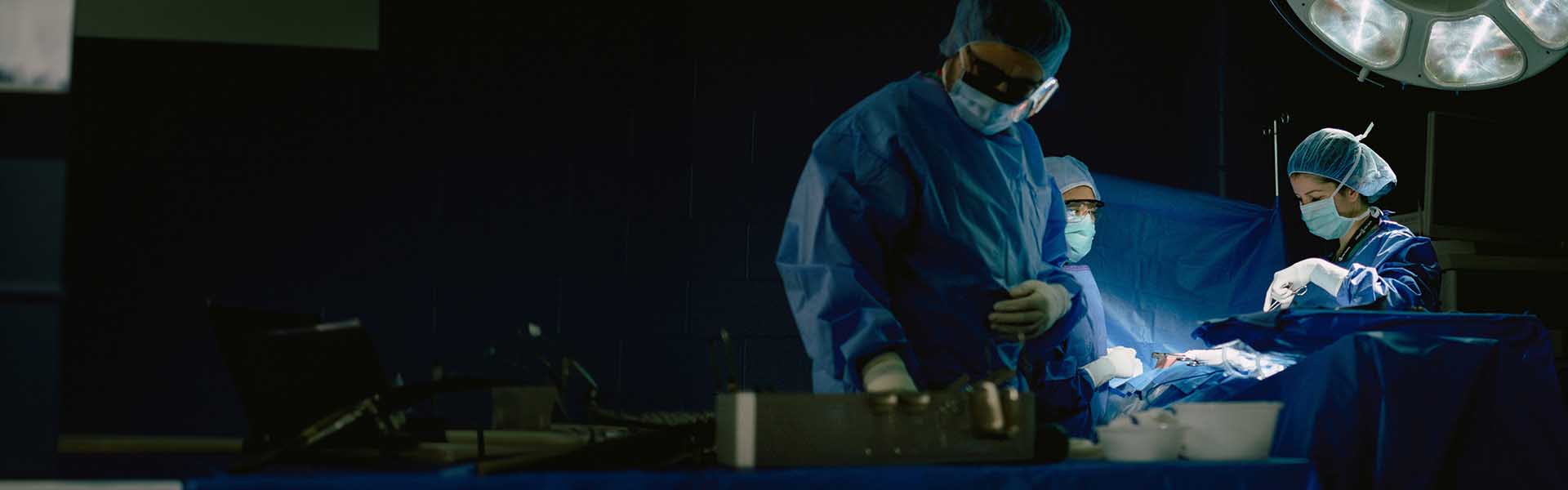 People in an operating room wearing scrubs.