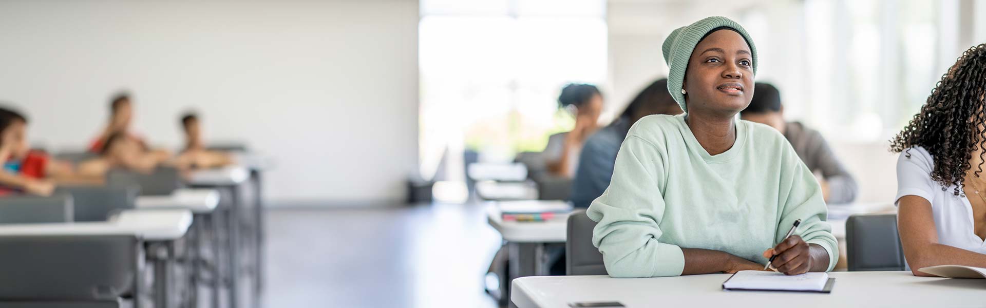 Female student listening in class while taking down notes