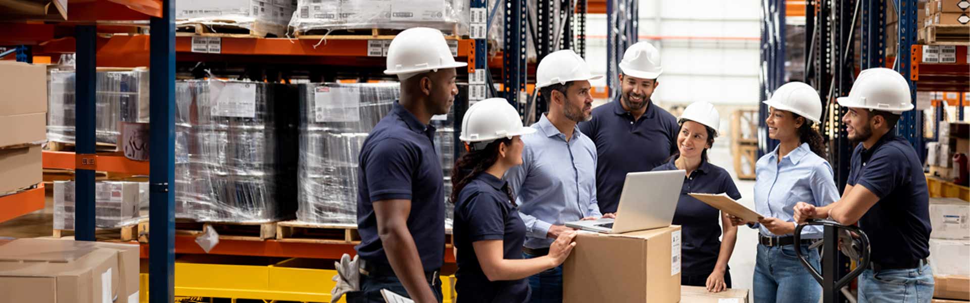 Supply chain management workers wearing white hardhats in a warehouse