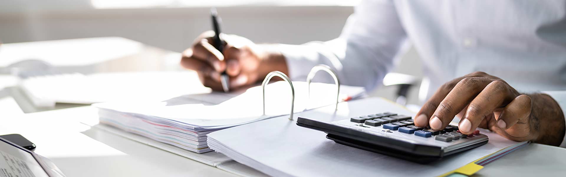 Student calculating invoice at desk using calculator