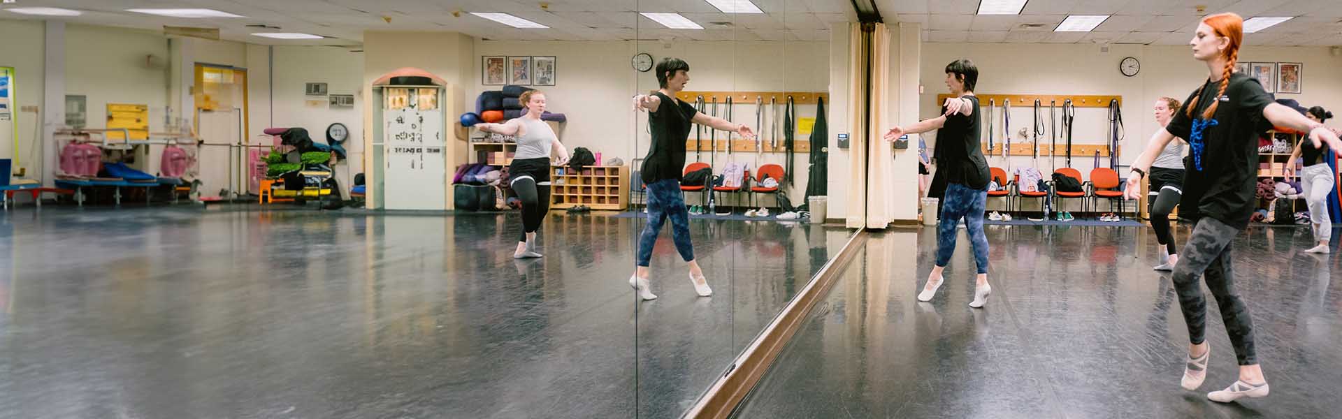 Students practicing their form in front of mirror in a dance class