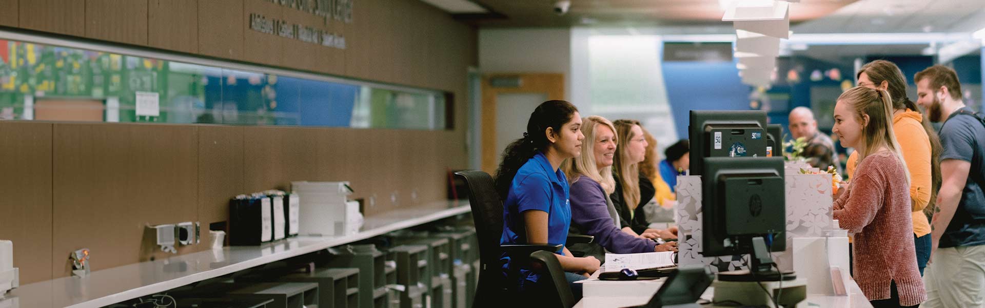 CLC employees and students standing across a desk from one another at the Welcome and One Stop