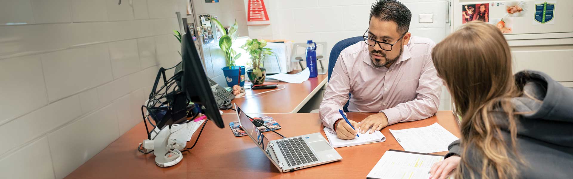 A student and a counselor in an office looking at a computer