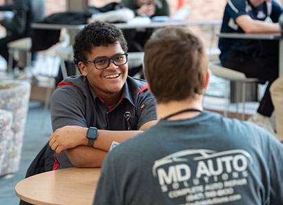 Two male students sitting at a table, talking.