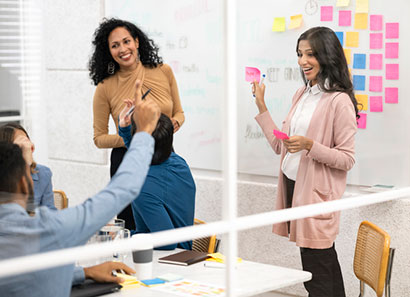 Two women lead employees in a training exercise using colorful sticky notes