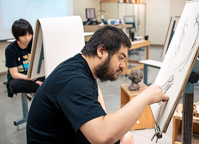 Students working on drawings on easels in classroom