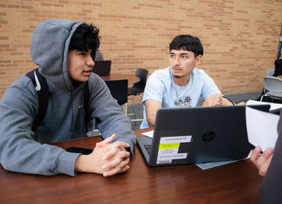 Two male students in discussion with laptop