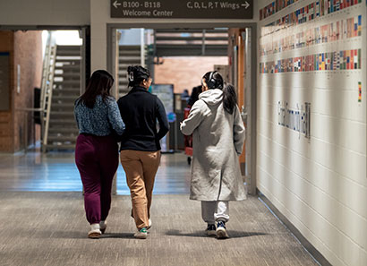 Three female students walking along a hallway