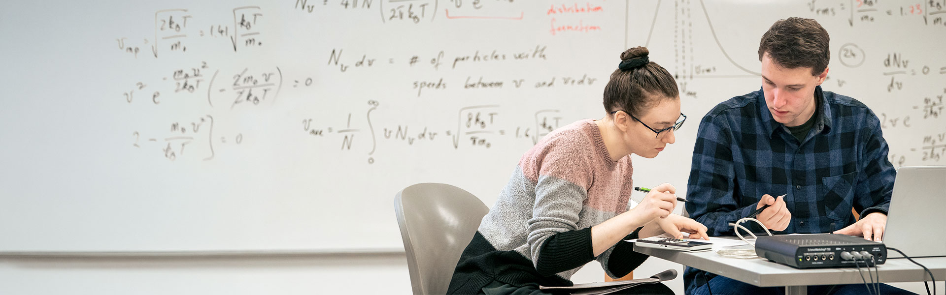 Students in classroom with whiteboard of math equations behind them