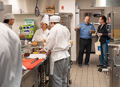 Community member getting a tour of the Prairie Restaurant kitchen while students hone their skills