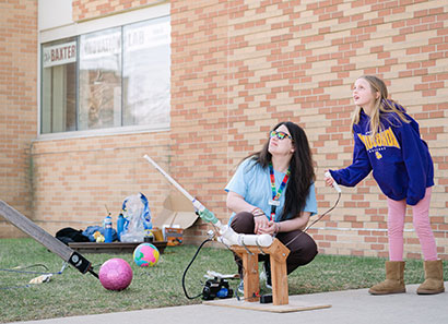 Open house attendee launching a rocket with CLC faculty assistance
