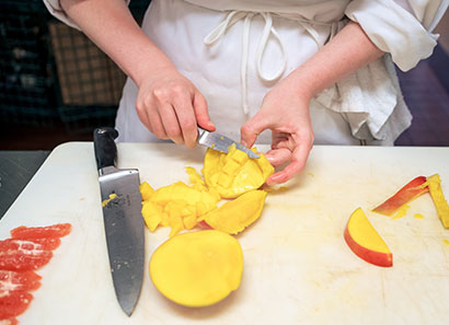 Close up of hands preparing a mango