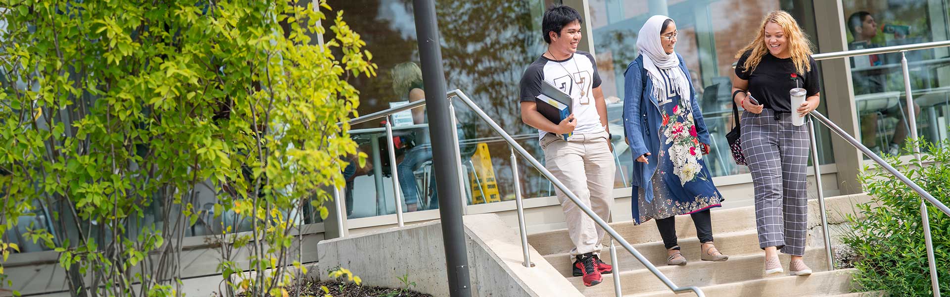Three students walking down steps on campus outdoors