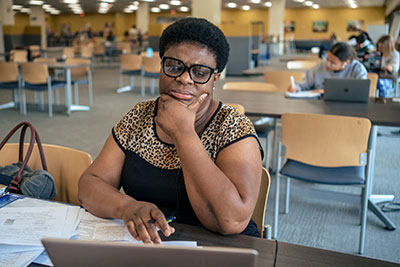An adult female student works on her laptop in the CLC library.