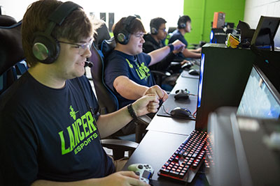 CLC esports team at computer stations doing a fist bump