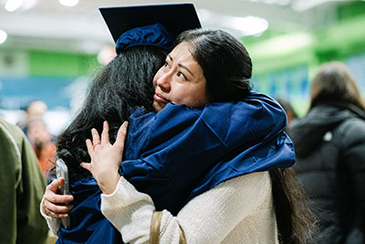 Parent hugging graduate after commencement ceremony