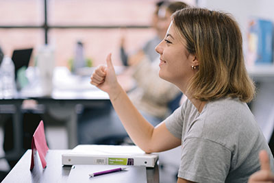 Smiling student giving the thumbs up in class