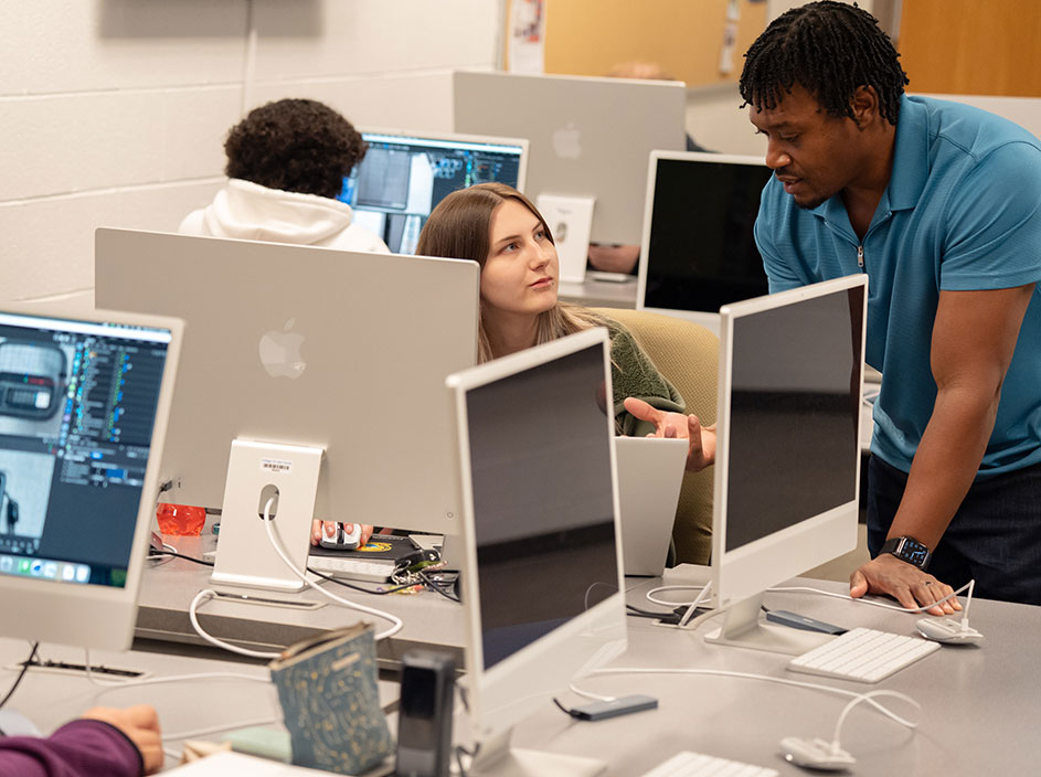 Student talking to instructor in computer lab