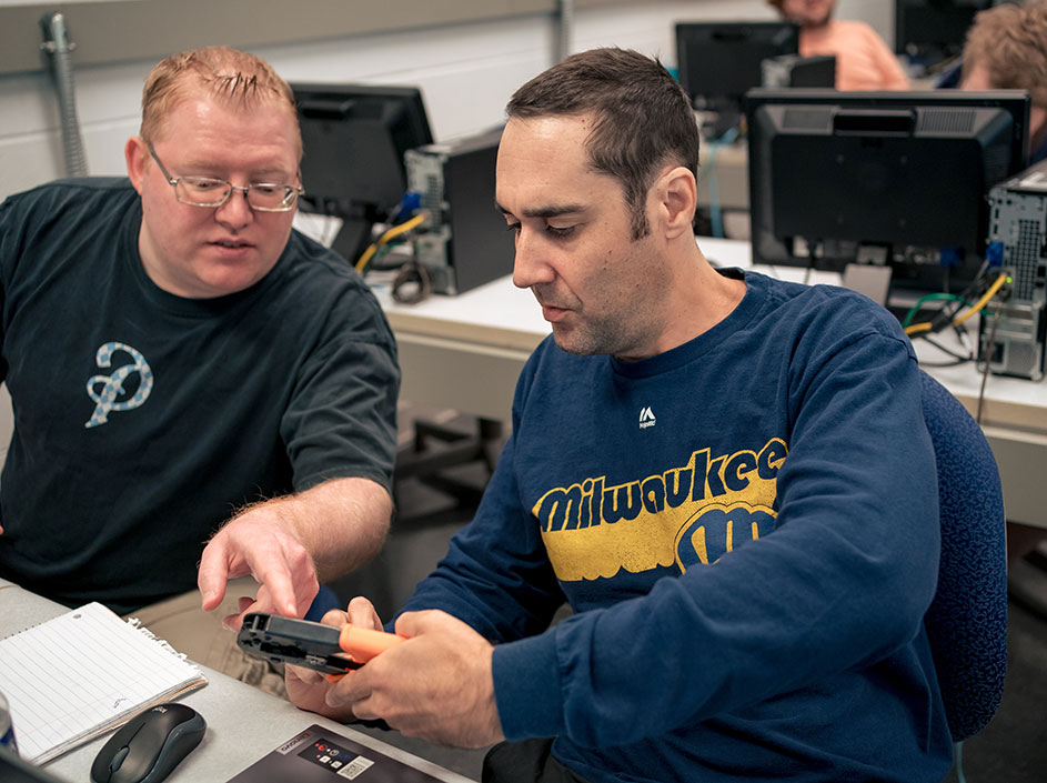Two adult students discussing a device in class.