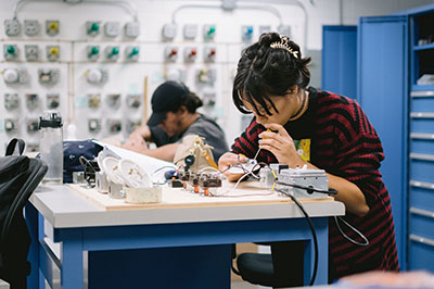 Students practicing HVAC skills at a worktable in the lab