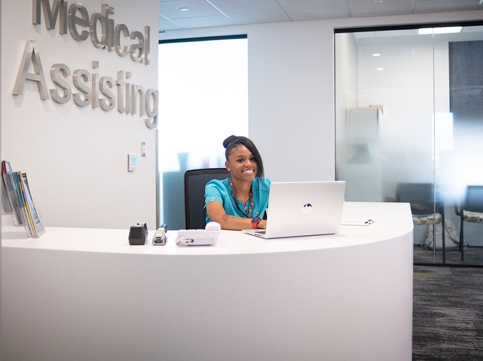 Smiling female student sitting behind medical reception desk