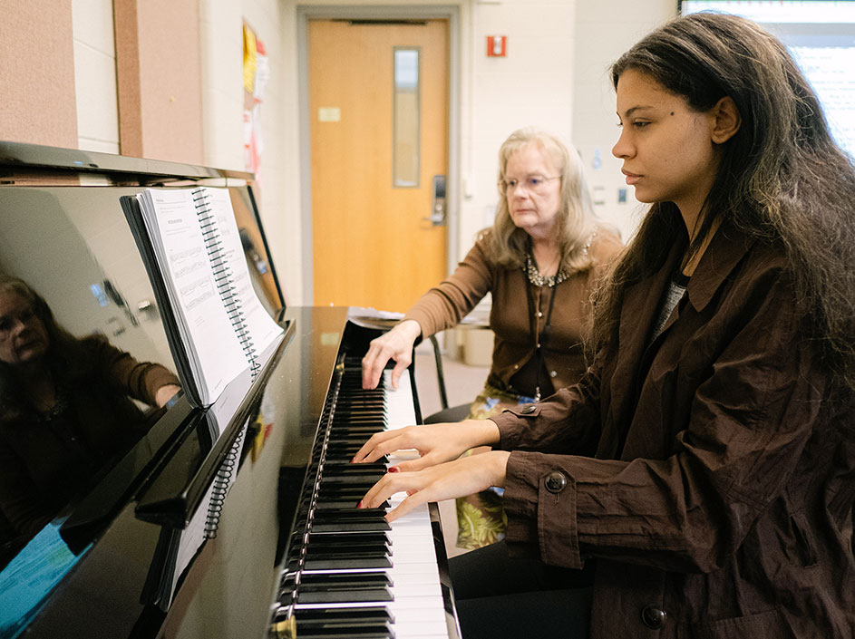 Student learning at the piano with teacher
