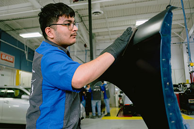 Student practicing vehicle refinishing skills