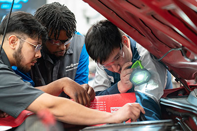 Students working under the hood of a car
