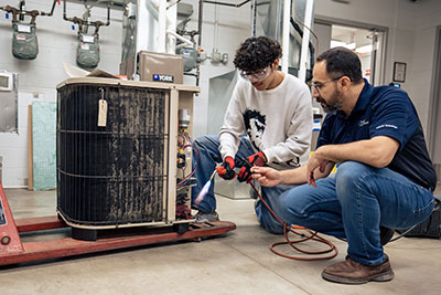 Student with blowtorch being instructed in HVAC work
