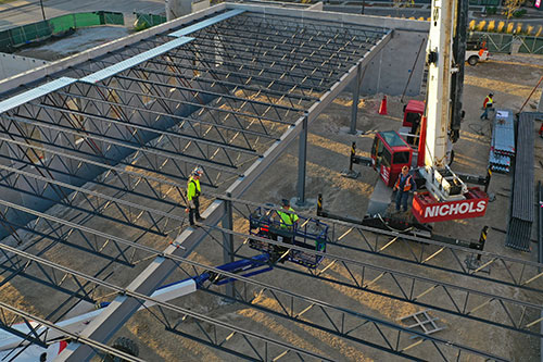 Construction worker walking on roof beams of new Urban Farm Center