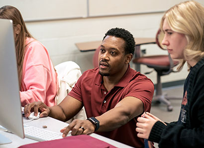 A CLC instructor working on a computer with a student